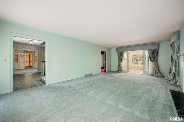 unfurnished living room featuring baseboards, visible vents, a chandelier, carpet floors, and ornamental molding