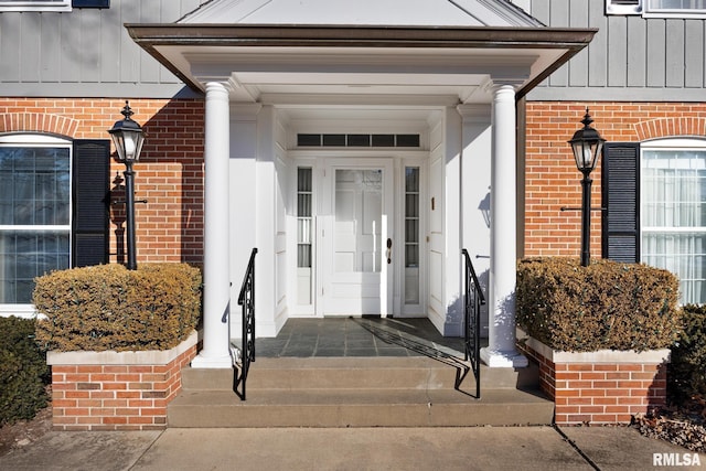 view of exterior entry featuring board and batten siding and brick siding