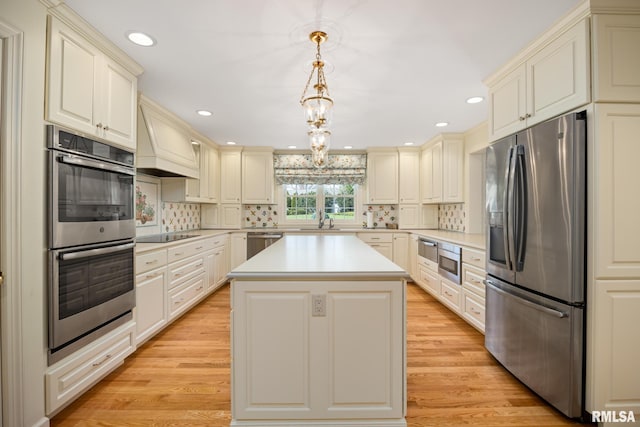 kitchen with a sink, light wood-style floors, stainless steel appliances, light countertops, and cream cabinetry