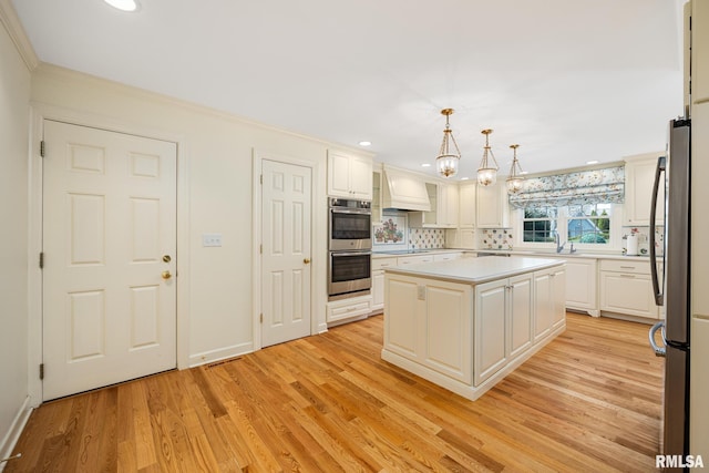 kitchen featuring light wood-style floors, decorative backsplash, custom range hood, light countertops, and appliances with stainless steel finishes