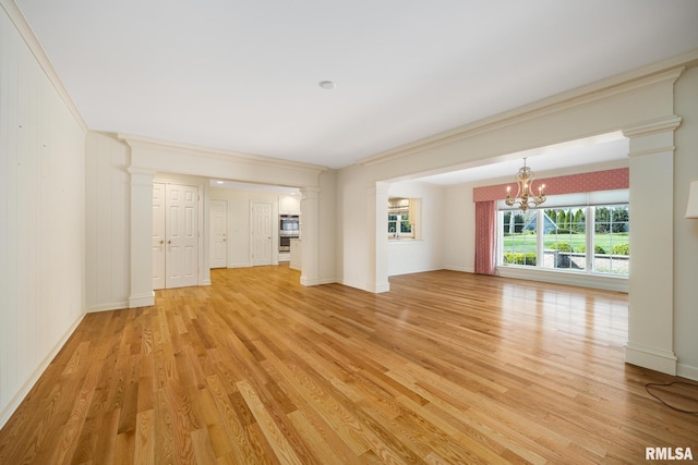 unfurnished living room with light wood-style flooring, an inviting chandelier, decorative columns, and ornamental molding