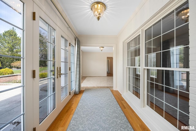 hallway featuring baseboards, crown molding, french doors, and wood finished floors