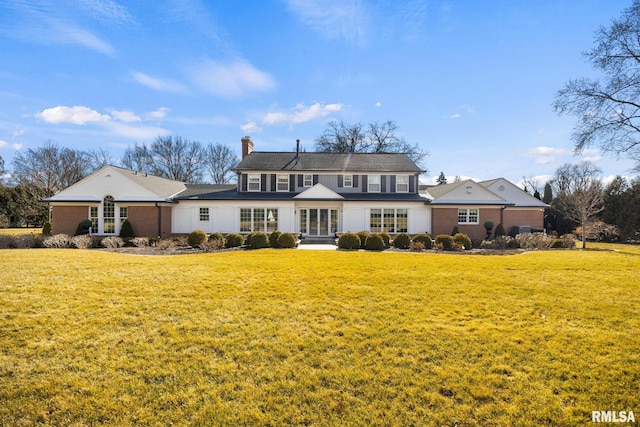 back of property with a chimney, brick siding, and a yard