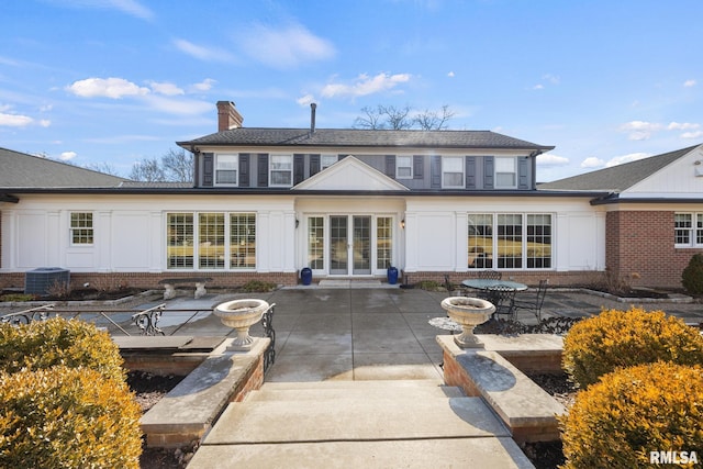 rear view of property featuring central air condition unit, a patio, brick siding, french doors, and a chimney