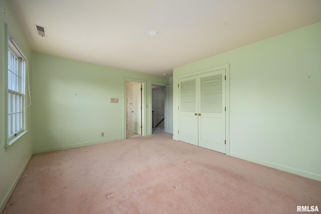 unfurnished bedroom with carpet, a closet, baseboards, and visible vents