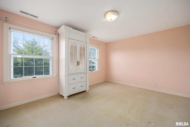 unfurnished bedroom featuring baseboards, visible vents, and light colored carpet