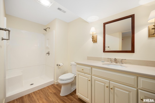 bathroom with visible vents, toilet, a shower, vanity, and wood finished floors