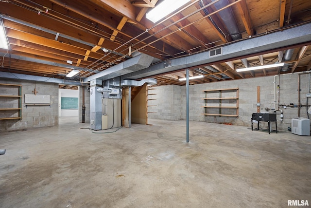 unfinished basement featuring heating unit, visible vents, and a sink