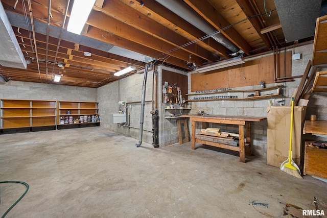unfinished below grade area featuring concrete block wall, a workshop area, and a sink