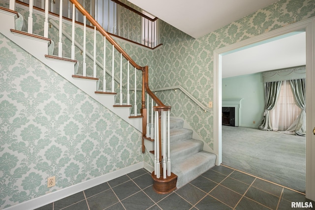 stairway with wallpapered walls, tile patterned flooring, a fireplace, baseboards, and carpet flooring