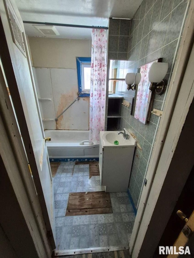 bathroom with visible vents, toilet, vanity, shower / tub combo with curtain, and tile walls
