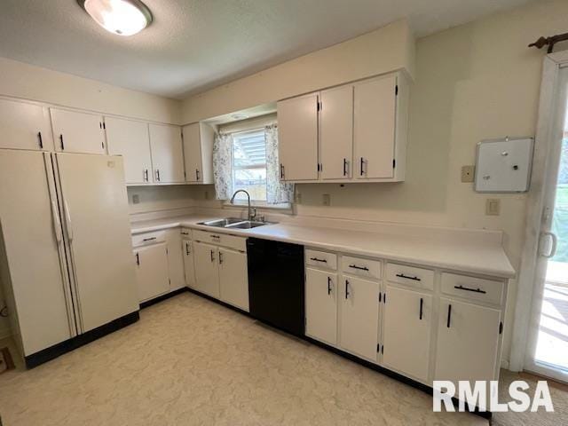 kitchen with white cabinets, light countertops, a sink, freestanding refrigerator, and black dishwasher