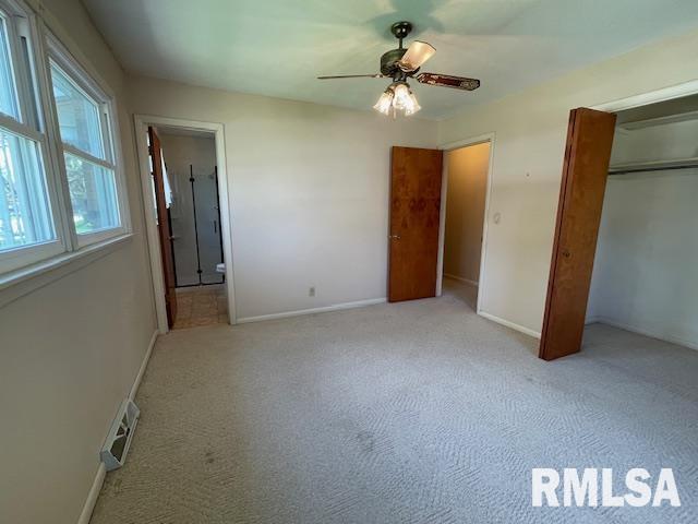 unfurnished bedroom featuring a closet, connected bathroom, carpet, baseboards, and visible vents