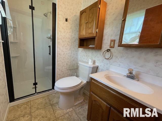 bathroom featuring wallpapered walls, vanity, toilet, and a stall shower