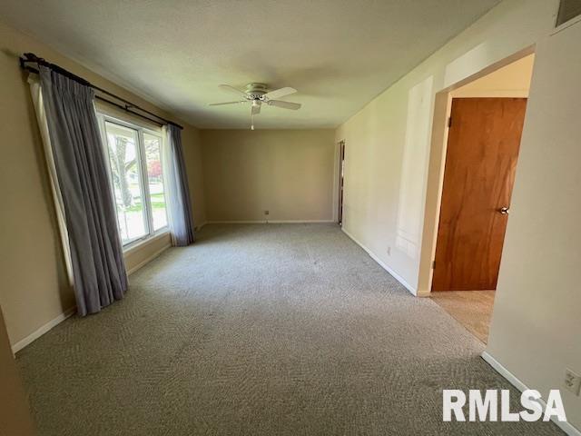 carpeted empty room with ceiling fan, baseboards, and visible vents