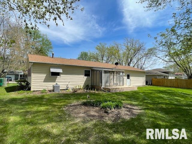 rear view of property with fence, a lawn, a sunroom, and central AC