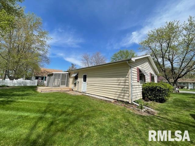 back of property featuring a sunroom, fence, and a lawn