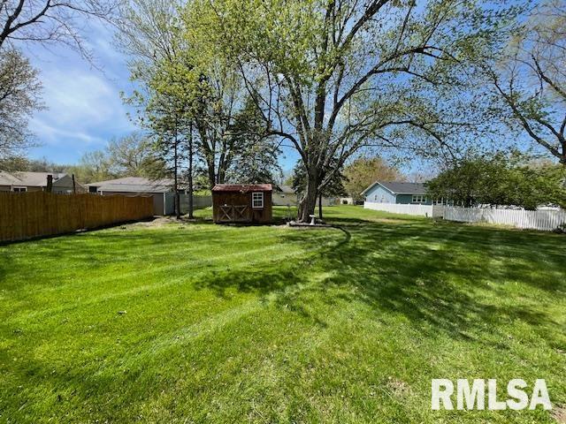 view of yard featuring fence, an outbuilding, and a storage shed