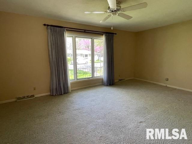 carpeted empty room featuring baseboards and a ceiling fan