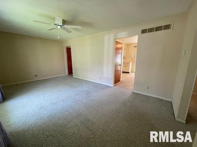 carpeted spare room featuring baseboards, visible vents, and ceiling fan