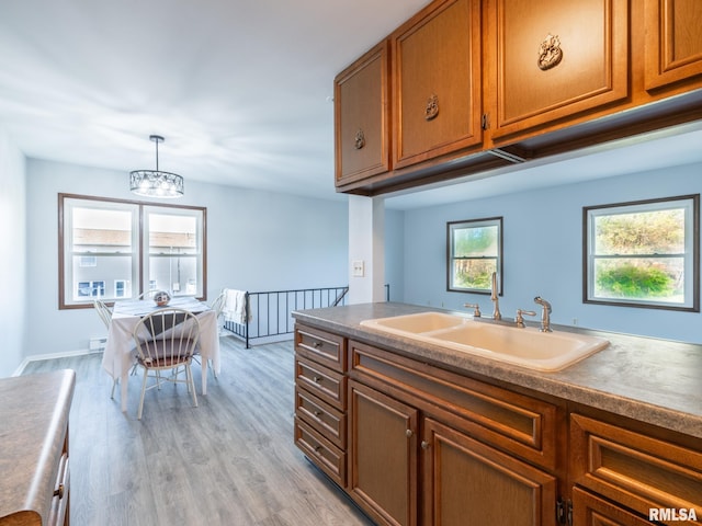 1024 Florence Ave, Pekin, IL 61554 - kitchen with a sink, brown cabinets, light wood-style floors, a chandelier, and pendant lighting
