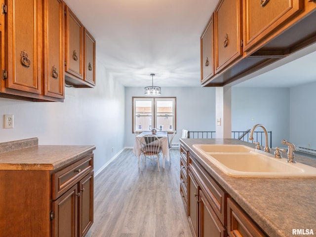 1024 Florence Ave, Pekin, IL 61554 - kitchen with a sink, brown cabinets, light wood-type flooring, a chandelier, and baseboards