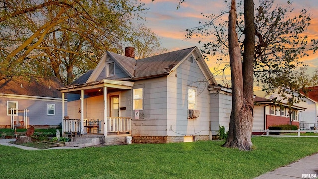 bungalow-style house featuring a porch, a front lawn, and a chimney