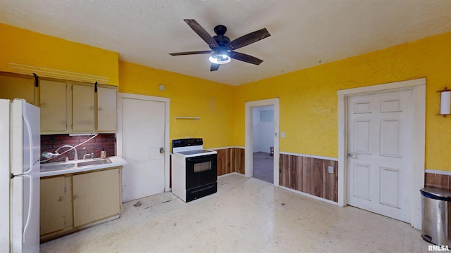 kitchen featuring a sink, wainscoting, range with electric stovetop, ceiling fan, and freestanding refrigerator