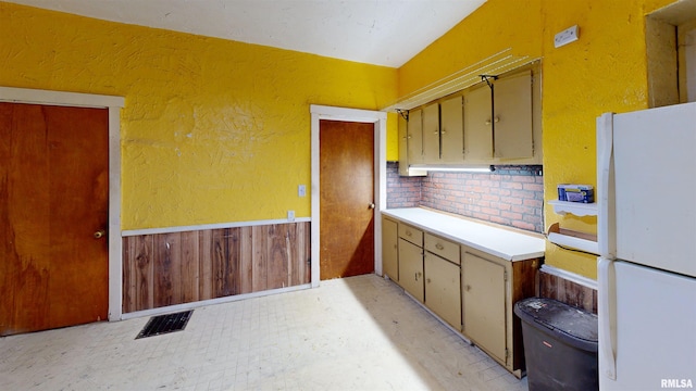 kitchen with visible vents, a textured wall, and freestanding refrigerator