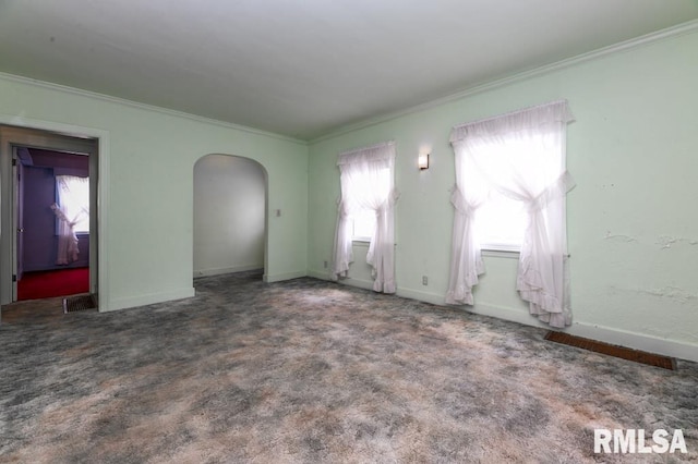 interior space featuring carpet flooring, visible vents, baseboards, ornamental molding, and arched walkways
