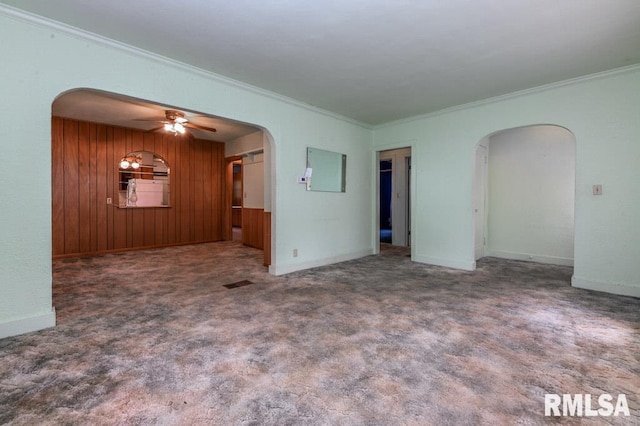 carpeted empty room with crown molding, a ceiling fan, and arched walkways