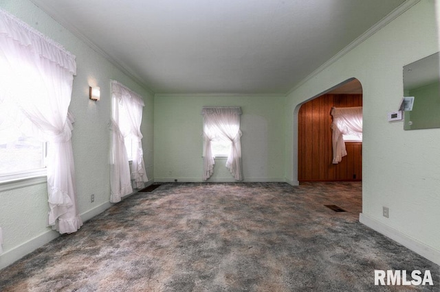spare room featuring carpet, crown molding, and arched walkways