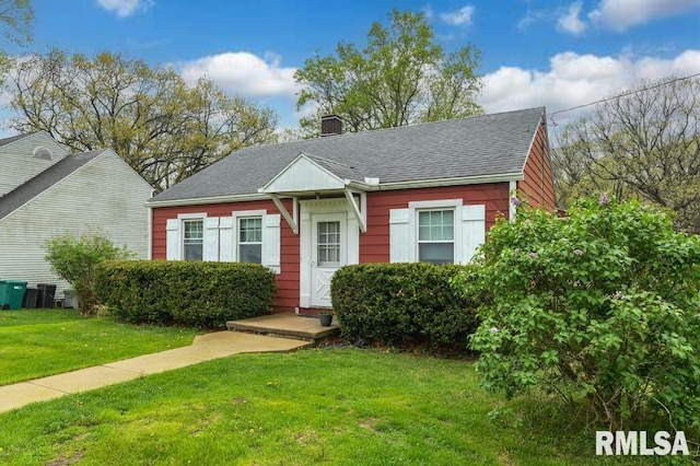 view of front of home with a chimney, a shingled roof, and a front lawn