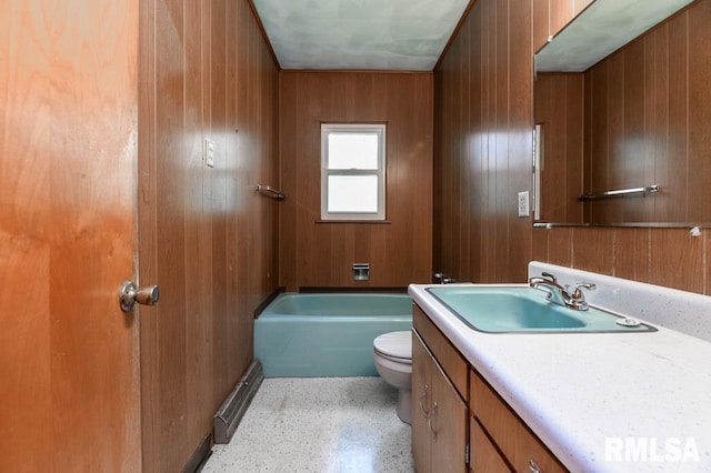 bathroom with wood walls, a tub to relax in, toilet, speckled floor, and vanity