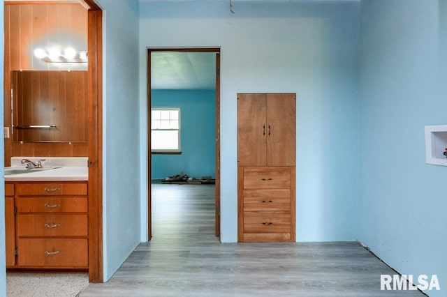 hallway with light wood finished floors and a sink