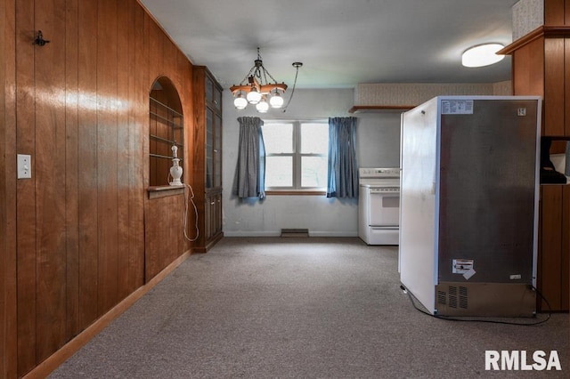 unfurnished dining area with wooden walls, a notable chandelier, and carpet flooring