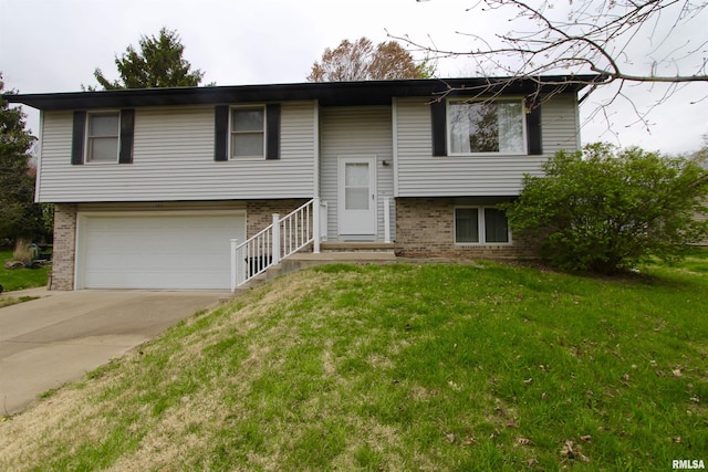 bi-level home with a front yard, driveway, a garage, and brick siding