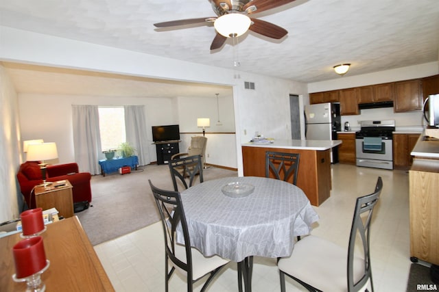 dining space featuring light floors, a textured ceiling, ceiling fan, and visible vents