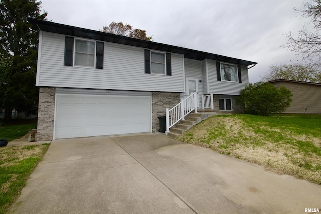 bi-level home featuring a front lawn, driveway, a garage, and brick siding