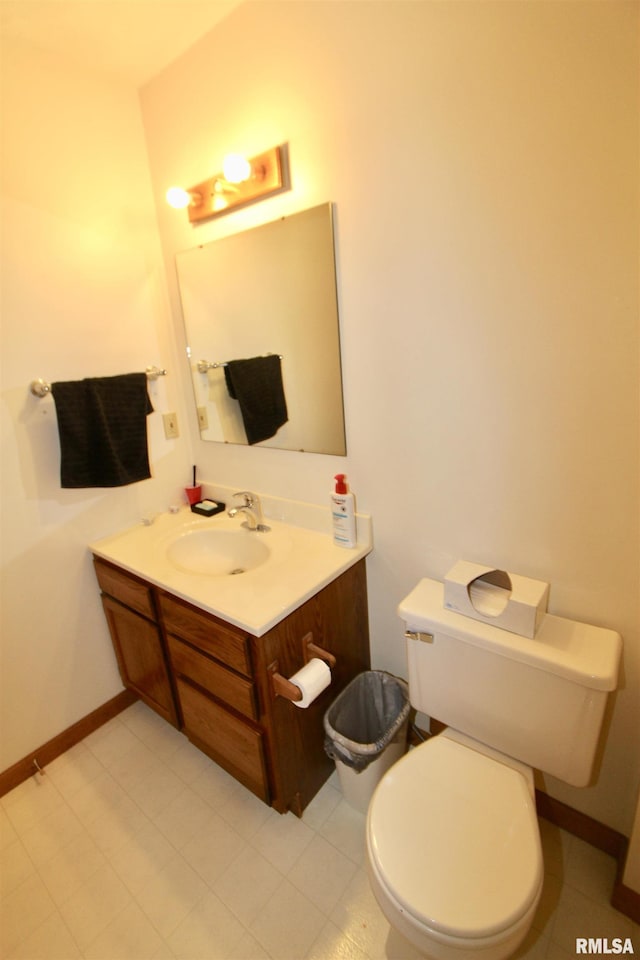 half bathroom featuring toilet, vanity, and baseboards