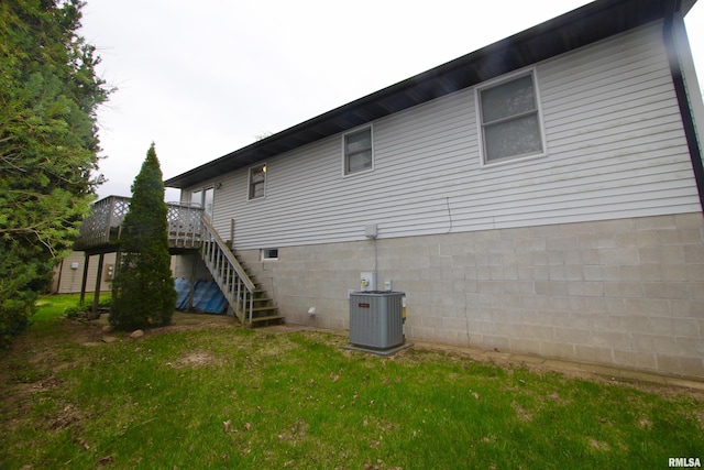 rear view of property with a lawn, cooling unit, and stairs