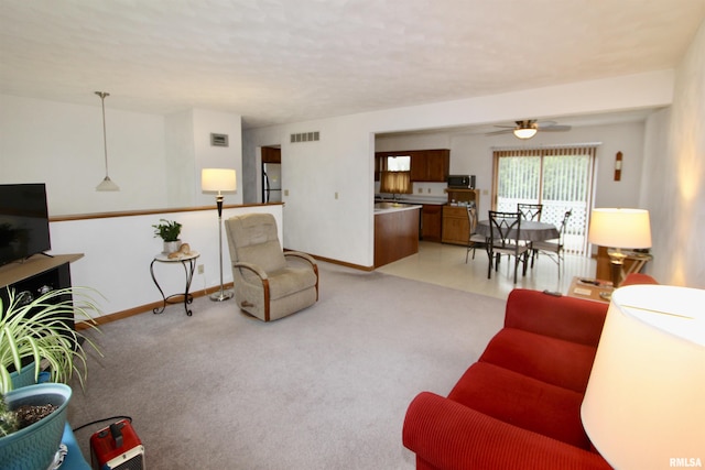 living area with visible vents, ceiling fan, light carpet, and baseboards