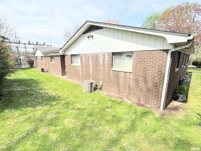 view of side of home featuring a yard, central AC unit, and brick siding