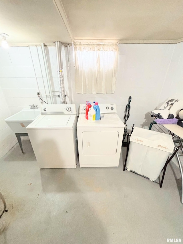 laundry area with concrete block wall, a sink, laundry area, and washer and clothes dryer