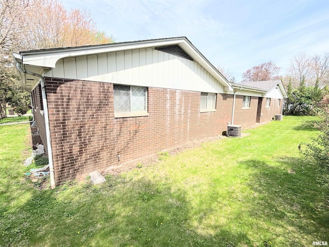 view of side of property featuring a lawn and brick siding