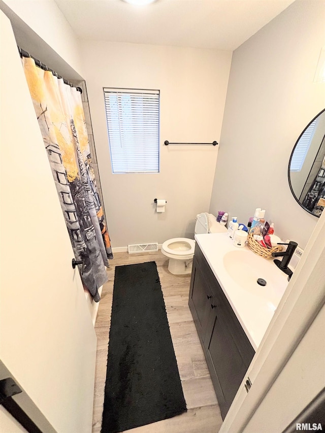 bathroom featuring wood finished floors, toilet, curtained shower, vanity, and visible vents
