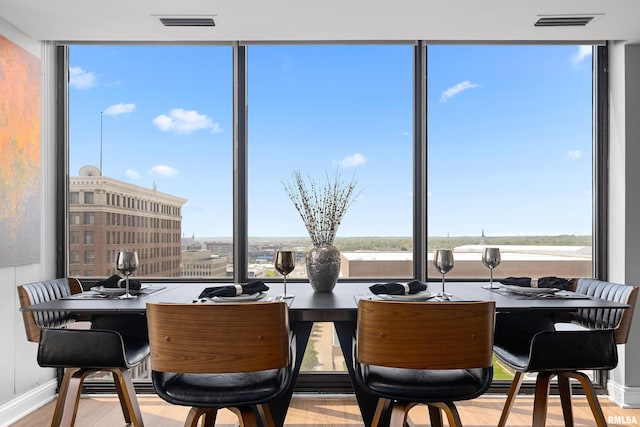 dining area featuring baseboards, visible vents, a healthy amount of sunlight, and wood finished floors