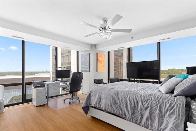 bedroom featuring visible vents, light wood finished floors, and expansive windows