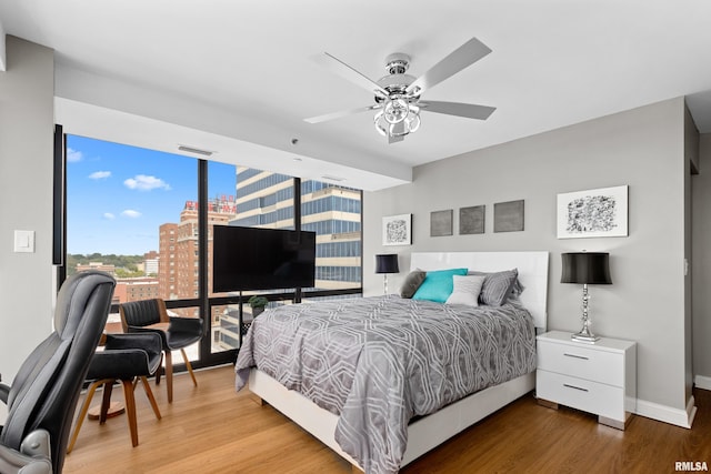 bedroom with visible vents, wood finished floors, baseboards, ceiling fan, and floor to ceiling windows