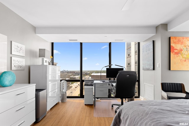 bedroom featuring visible vents, refrigerator, floor to ceiling windows, and light wood finished floors